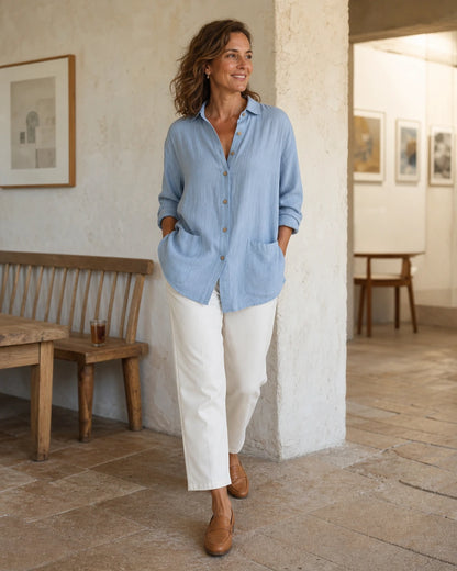 Women's blue relaxed longline shirt in an architectural lifestyle setting.